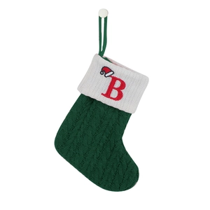 Close-up of green knitted Christmas stocking with white cuff and red letter B embroidery