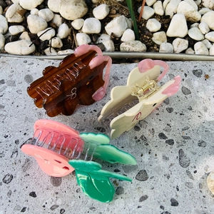 Detailed view of bear-shaped and floral hair claws in assorted colors on a textured surface