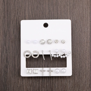 Nine pairs of silver alloy stud earrings with pearls and rhinestones on a card