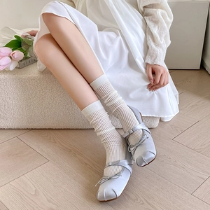 Close-up of white vertical striped slouch socks paired with blue silk Mary Jane shoes