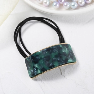 Detail of emerald marble acetate hair tie with golden metal frame and elastic band