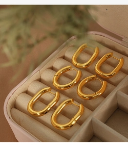Close-up of three pairs of polished gold U-shaped earrings in a pink velvet jewelry box
