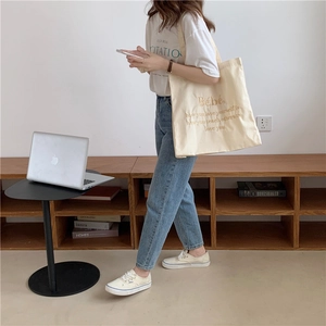 Makroansicht der beigen Canvas-Tragetasche mit braunem, gesticktem Spruch für Damen