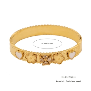 Detail of gold stainless steel bangle with white shell floral and heart motifs