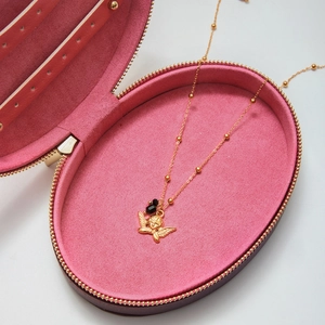 Dettaglio della collana con ciondolo angelo dorato e perle nere in scatola di velluto rosa