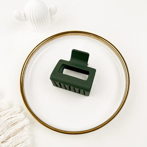 Detail of a dark green matte square hair claw clip placed on a decorative white tray