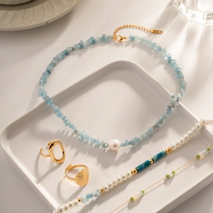 Detail of sea blue gravel and pearl necklace with golden stainless steel rings