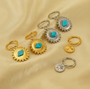 Detailansicht goldener und silberner Ohrringe mit Sonnenmuster und Türkis-Einlagen