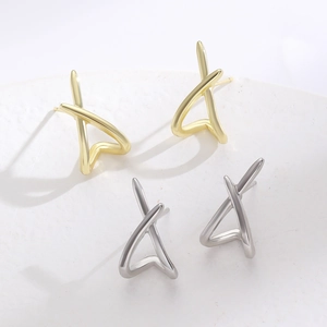 Makroansicht minimalistischer X-förmiger Ohrstecker in Gold und Silber auf weißem Ständer