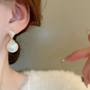 Detailed view of elegant gold-plated pearl drop earrings with sparkling zircon stones