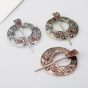 Detailed view of three Celtic knot metal brooches in silver, bronze, and copper finishes