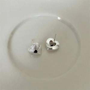 Macro view of S925 sterling silver heart earrings with black inlay and wave texture
