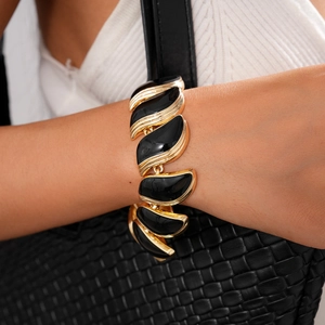Détail d'un bracelet gourmette vintage doré avec des incrustations de feuilles noires