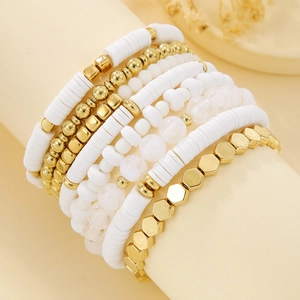 Detail of stacked boho bracelets with white heishi clay beads and golden metal accents