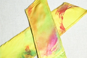 Detailed close-up of colorful tie-dye fabric textures and stitched edge on the dress