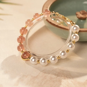 Detail of strawberry crystal beads with pearls and golden accents on a textured base