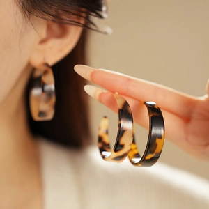 Macro detail of tortoiseshell resin C-shaped hoop earrings with polished amber texture