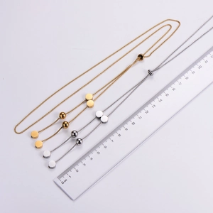 Measurement of gold and silver double-layered beaded necklace length against a ruler