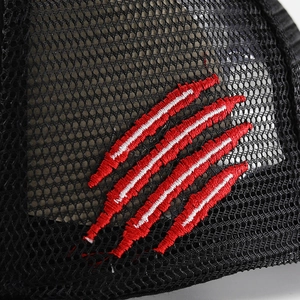 Macro shot of breathable black mesh fabric and red claw embroidery on hip hop hat