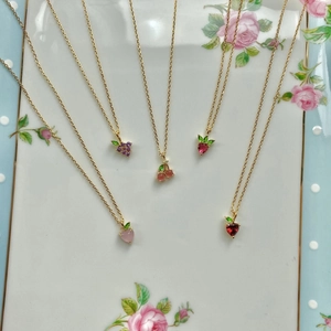 Detail showing tropical fruit pendants with colorful crystals and gold-plated chains