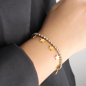 Close-up of a gold star charm bracelet with sparkling zircons worn on a female wrist