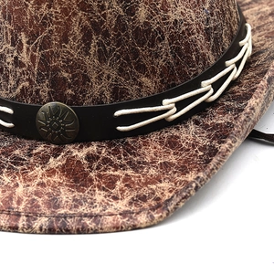 Detailed macro view of brown faux suede western cowboy hat with cracked texture and bronze buckle