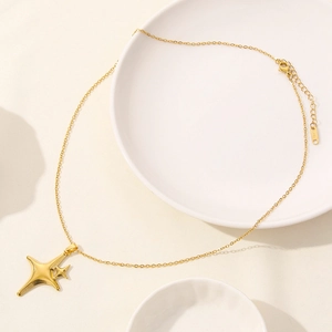Detail of gold star pendant necklace with 18k plating on elegant ceramic tray