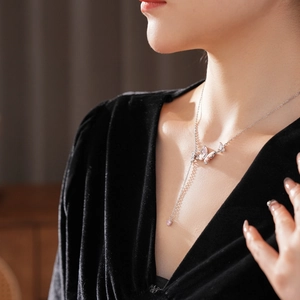 Collier argenté avec papillon et pampille cœur rose porté par un mannequin femme