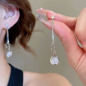 Detail of silver star earrings featuring long tassels and white cat's eye stone beads