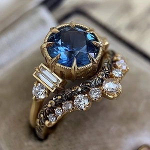 Vintage golden ring set with deep blue gemstone, diamonds and floral engraving in jewelry box