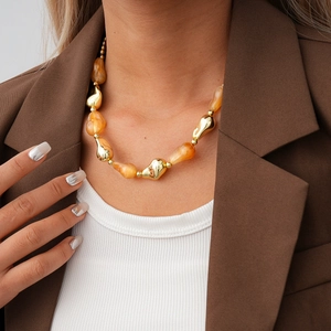 Detail of chunky acrylic beaded necklace with geometric gold accents on female model
