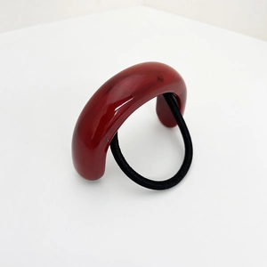 Détail d'un élastique à cheveux en résine rouge en forme de U au style vintage
