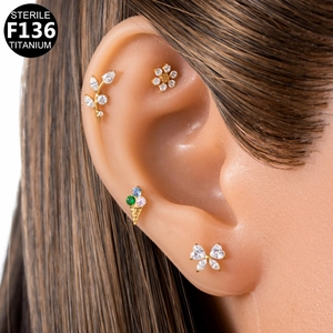Golden F136 titanium earring set featuring leaf, flower and bow designs with crystals