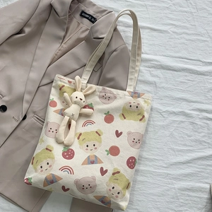 Flache Ansicht der cremefarbenen Canvas-Tasche mit Comic-Prints und Hasen-Anhänger