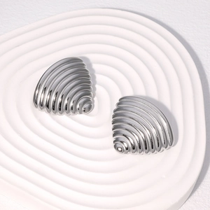 Macro shot of silver geometric triangle stud earrings with textured ridges on a white stand