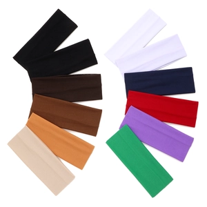 Twelve solid color elastic wide headbands for sports and yoga arranged in a curved row