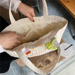 Detailed interior of the white quilted tote bag featuring embroidery and inner pockets