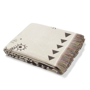 Detailed close-up of bohemian woven throw blanket with black geometric patterns and colorful fringe