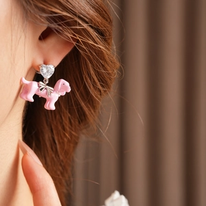 Close-up of pink dachshund earring with a heart diamond and bow on a female ear
