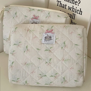 Detail of floral quilted cosmetic bag featuring pink bow and elephant fabric label