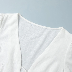 Close-up of the breathable cotton-linen fabric texture and V-neckline of a white summer top