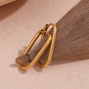 Detail of 18K gold-plated oval hoop earrings displayed on a natural wooden branch