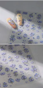 Detail of 5D embossed nail stickers featuring blue bows and heart patterns on M-623 sheet