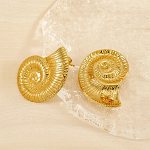 Macro detail of vintage gold conch earrings showing spiral textures on silk background