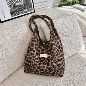 Macro detail of leopard print faux shearling tote bag on cozy ivory fleece sofa