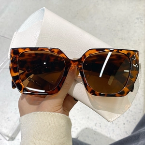 Detail of tortoise shell texture and dark brown lenses on oversized square sunglasses
