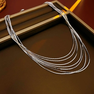 Detail of silver multi-layer herringbone chain necklaces displayed in a brown jewelry box
