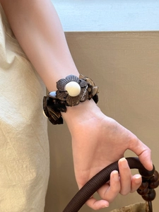 Detail view of bohemian brown coconut shell floral bracelet worn on a model wrist