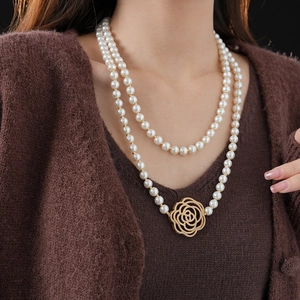 Double-layered pearl necklace featuring a golden hollow flower pendant on model