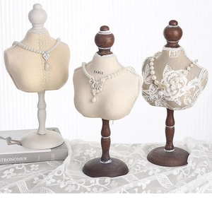 Detailed view of three vintage mannequin necklace stands with lace and floral accents